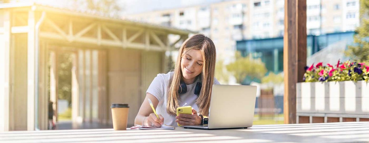 Female student sitting working on her laptop at a table.