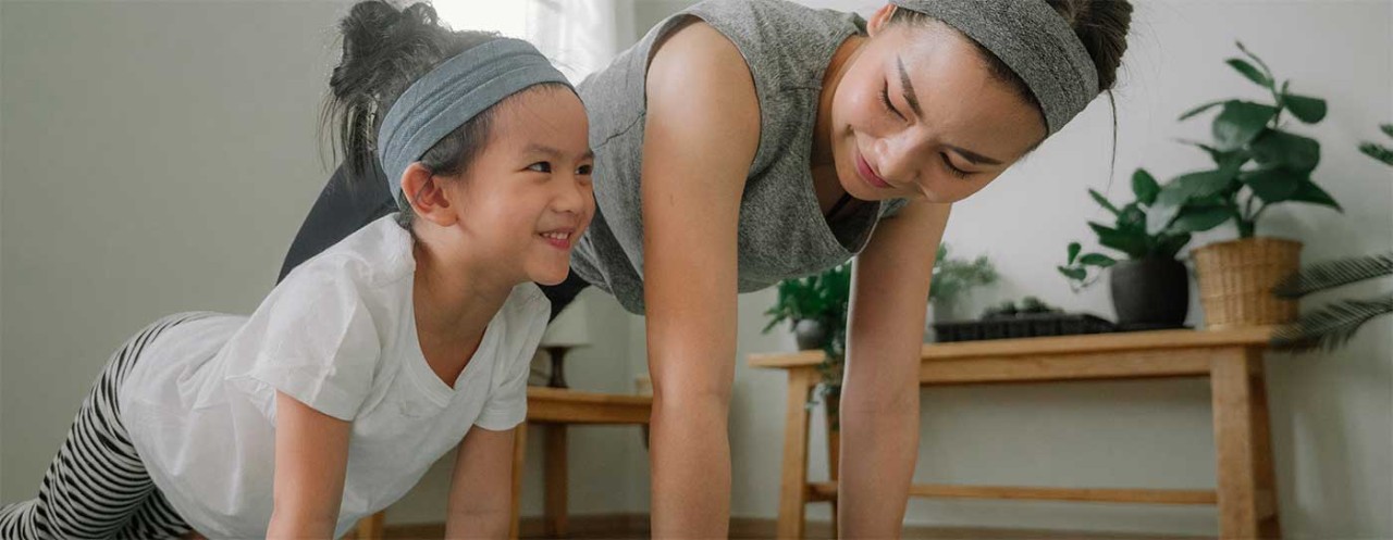 Mother and young daughter holding a plank pose.