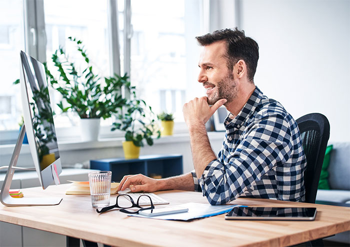 Man seated at his desk looking at computer monitor.