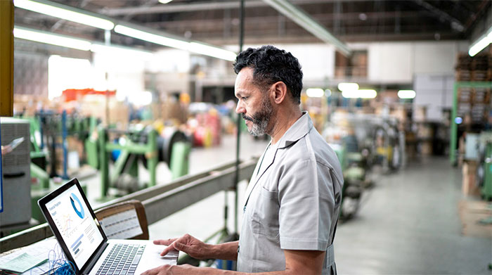 Man working on a computer in a manufacturing plant.