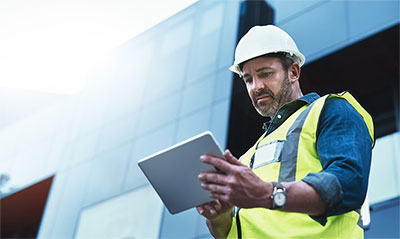 Man wearing hardhat looking at tablet computer.
