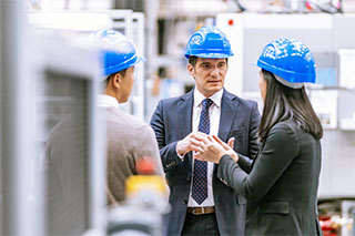 3 business people wearing hardhats.
