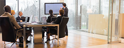 Man pointing at screen at a meeting presentation.