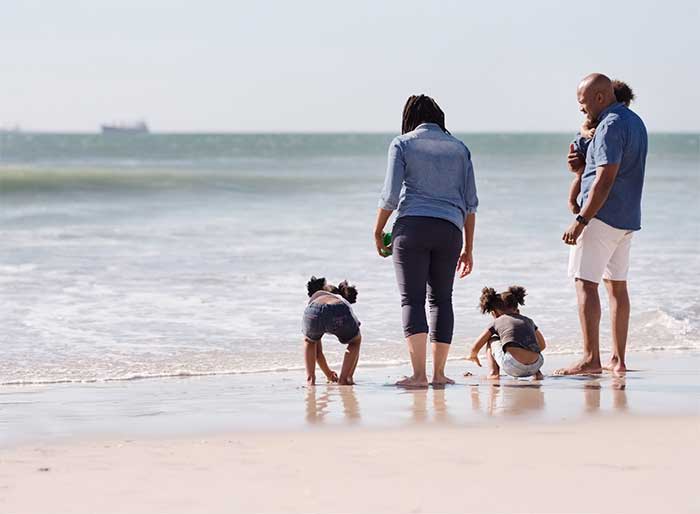 Family on beach playing at water's edge.