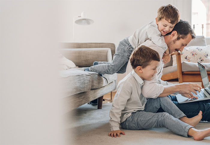 Two boys jumping on their father's back.