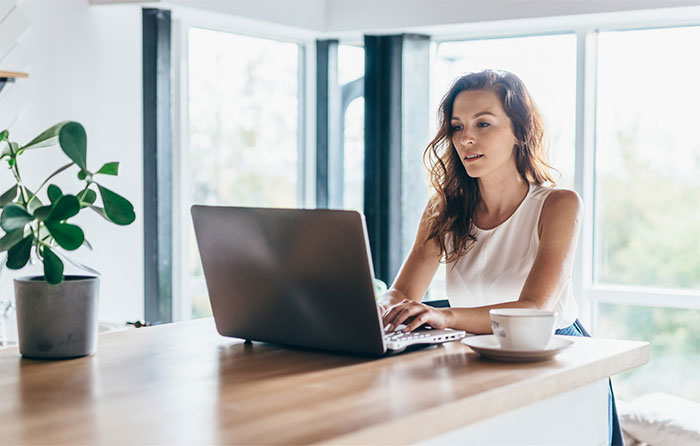 Woman with coffee working on laptop.