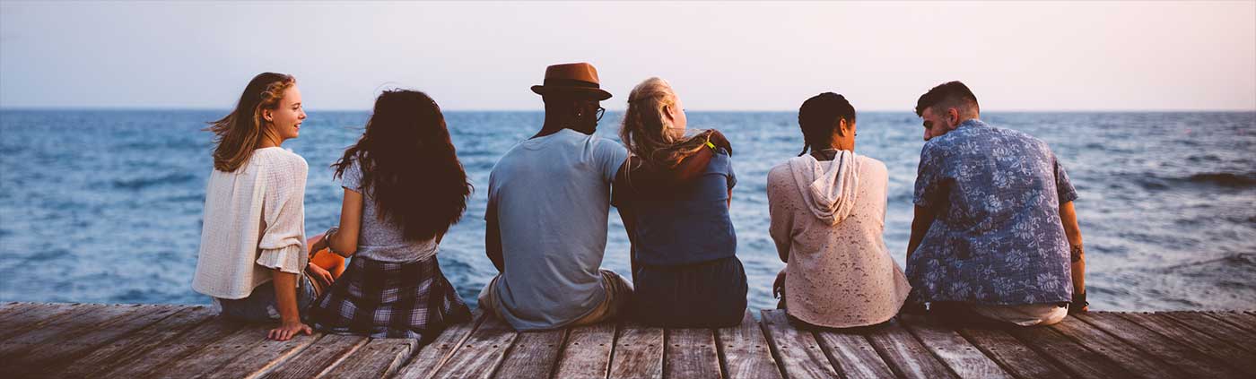 Friends sitting on the dock looking at the ocean.