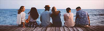 Friends sitting on the dock looking at the ocean.