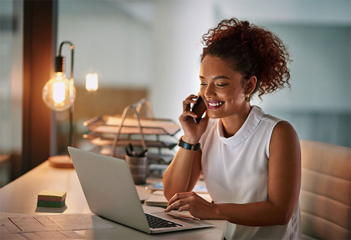 Woman talking on telephone and using laptop at the same time.