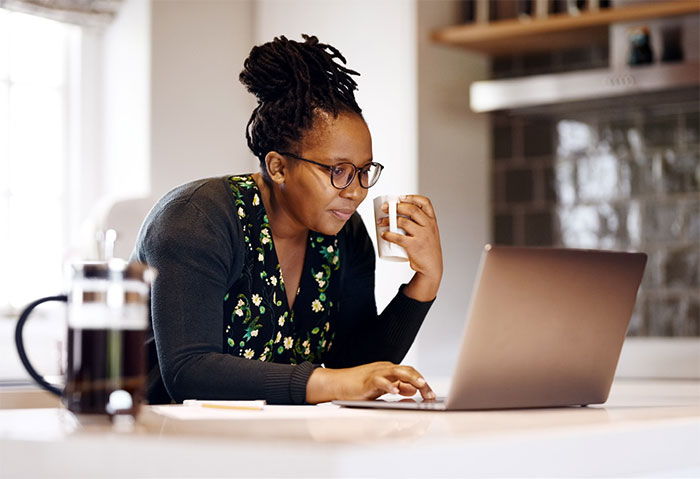 Woman at table working on laptop computer.