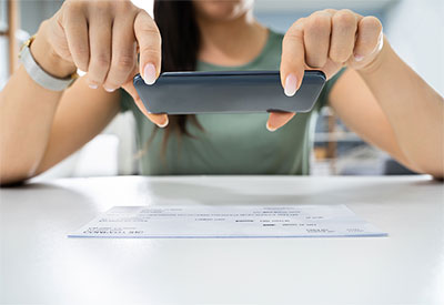 Woman using smartphone camera to take picture of check and use mobile deposit.