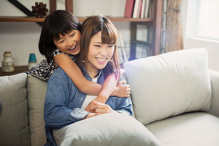 Young girl hugging her sister from behind.