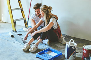 Newlyweds looking at laptop and painting room