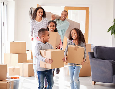 Young family carrying moving boxes into new home.