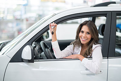 Woman in driver's seat of car leaning against the steering wheel.