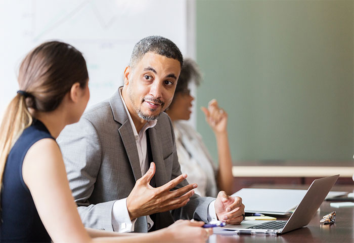 Man talking to client at desk.